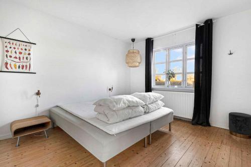 a bedroom with a bed with white sheets and a window at A Lovely Holiday Home In Quiet, Scenic Surroundings in Rønne