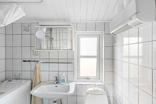 een witte badkamer met een wastafel en een raam bij Cozy Holiday Home Close To Forest And Beach in Hasle
