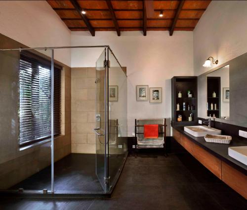 uma casa de banho com uma cabina de duche em vidro e um lavatório. em ama Stays & Trails The Mango House, Alibag em Alibag