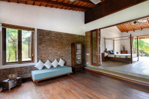 uma sala de estar com um sofá e um quarto em ama Stays & Trails The Mango House, Alibag em Alibag