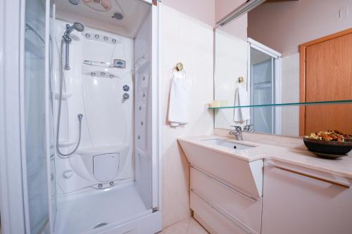 La salle de bains blanche est pourvue d'une douche et d'un lavabo. dans l'établissement Loft Diamante, à Soiano del Lago