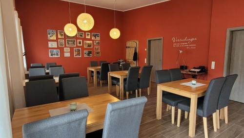 a dining room with tables and chairs and red walls at Torhaus Terra Nova in Elsterheide