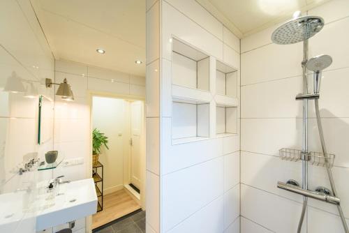 a white bathroom with a shower and a sink at De Klokkenluider in Hollum
