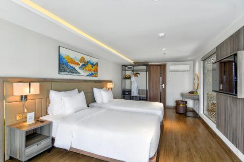 a bedroom with a large white bed and a television at Maris Hotel Nha Trang in Nha Trang