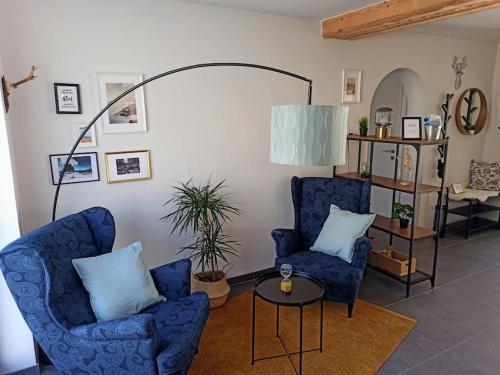 een woonkamer met twee blauwe stoelen en een tafel bij DAS TONIS - IHR Bett im Herzen des Salzkammergutes in Bad Goisern