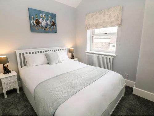 a bedroom with a large white bed and a window at Babbling Brook Cottage in Stony Middleton