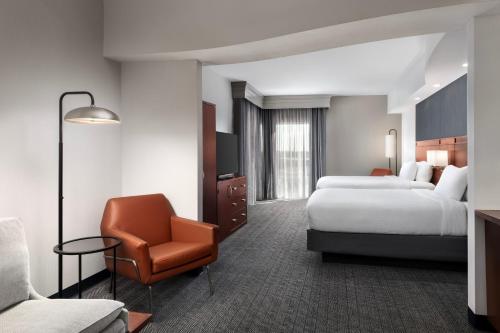 a hotel room with two beds and a chair at Courtyard By Marriott Little Rock North in North Little Rock