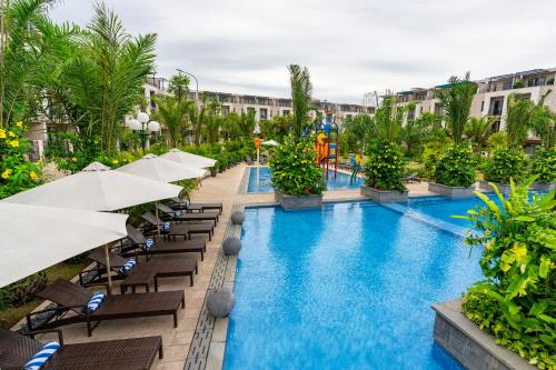 einen Infinity-Pool in einem Resort mit Stühlen und Sonnenschirmen in der Unterkunft Villa 102 royal lotus, Hùng Thắng, Hạ Long, Quảng Ninh in Hạ Long