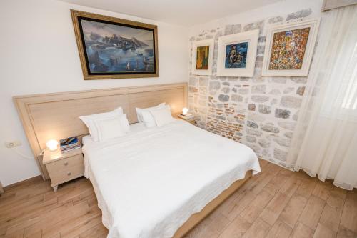 a bedroom with a white bed and a stone wall at Apartmani Art Karampana in Kotor