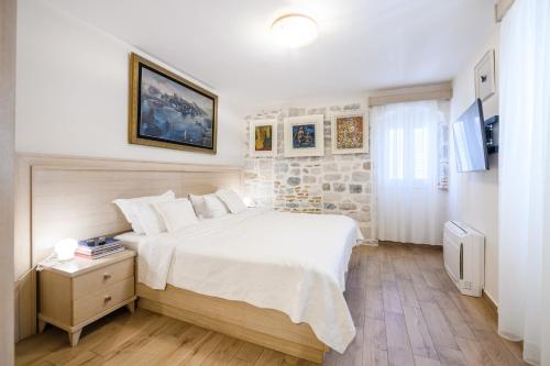 a bedroom with a large white bed and a table at Apartmani Art Karampana in Kotor