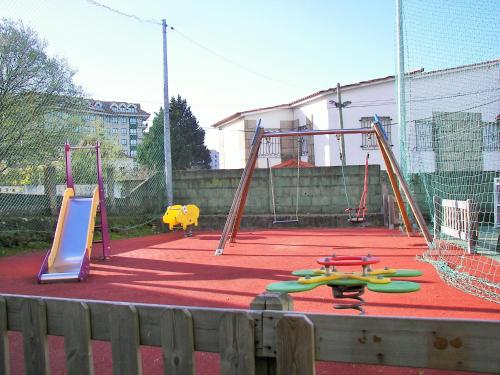 un parque infantil vacío con dos columpios y toboganes en Hostal Santa Marta Playa, en Baiona