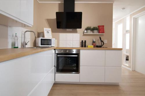 a kitchen with white cabinets and a microwave at Well-Equipped Apartment with Stunning Views in Bodø