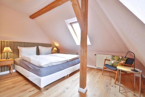 a attic bedroom with a bed and a chair at Ferienwohnung an der Brunnenaue in Stralsund
