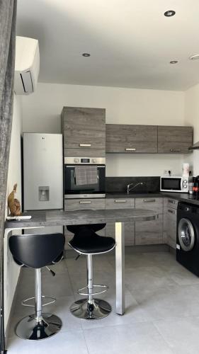 une cuisine avec deux tabourets de bar et un comptoir dans l'établissement N2 Maison T2 climatisé, à Ajaccio