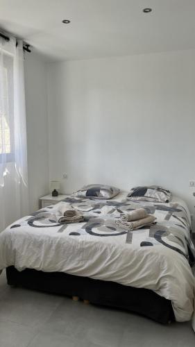 une chambre avec un grand lit dans une pièce blanche dans l'établissement N2 Maison T2 climatisé, à Ajaccio