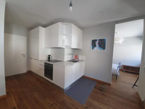a kitchen with white cabinets and a wooden floor at Appartamento Fidanza 4 in Brissago Center in Brissago