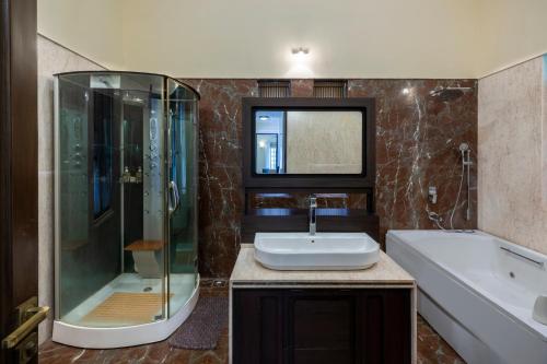 a bathroom with a sink and a shower and a tub at amã Stays & Trails Villa No 1, Goa in Old Goa