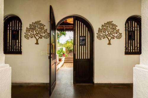 an open door to a house with trees on the wall at amã Stays & Trails Villa No 1, Goa in Old Goa