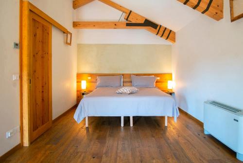 una camera da letto con letto, lenzuola bianche e pavimenti in legno di La Barchessa a Corva
