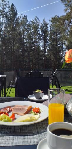 a table with a plate of food and a glass of orange juice at Panorama Hotel Noszvaj in Noszvaj