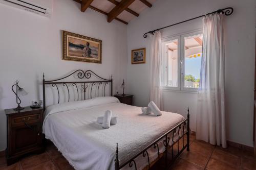 um quarto com uma cama com lençóis brancos e uma janela em Villa S'illot 105 By MENORCARENTALS em Son Bou