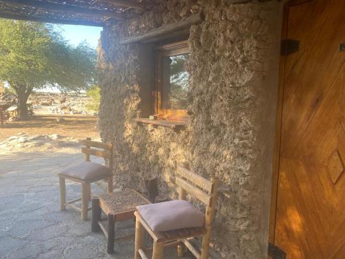 two benches sitting outside of a stone building with a window at El Huarango Eco retreat in La Huaica