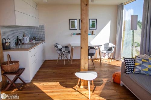 a kitchen and living room with a couch and a table at BioDomek, naturalny dom z przepięknymi widokami na góry in Gniewoszów