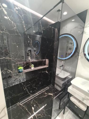 a black marble bathroom with a sink and a mirror at Grey Luxury Apartment in Gjirokastër