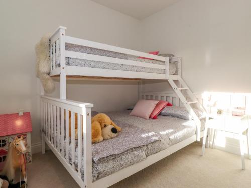 a white bunk bed with a teddy bear laying on it at Stone Croft House in Chathill