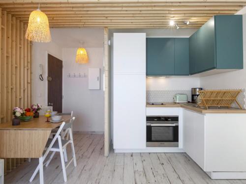 une cuisine avec des armoires blanches et une table en bois dans l'établissement Superbe studio face à la mer accès direct plage, à Biarritz