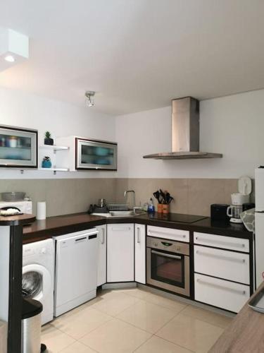 une cuisine avec des armoires blanches et un four à plaques de cuisson dans l'établissement Appartement La Tranquillité, 2mn à pieds mer, à Fréjus