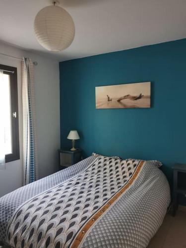 une chambre avec un lit avec un mur bleu dans l'établissement Appartement La Tranquillité, 2mn à pieds mer, à Fréjus