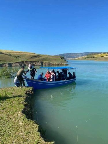 a group of people in a blue boat on a river at دوار ابغاوة ازغيرة تروال سد الوحدة وزان in Ouazzane