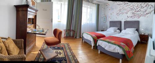 una camera d'albergo con due letti e un divano di Chambres d'hôtes Le Relais de la Perle a Le Vernois