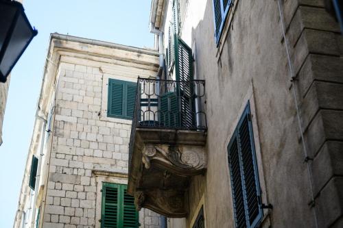 an old building with a balcony and green shutters at Apartmani Art Karampana in Kotor