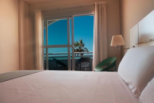 a bedroom with a bed and a window with a view at Hotel Vértice Chipiona Mar in Chipiona