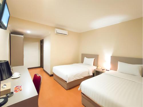 a hotel room with two beds and a desk at KAWANA HOTEL in Kampungdurian