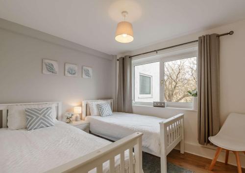 a bedroom with two beds and a window at Ty Golau in Llanbedrog