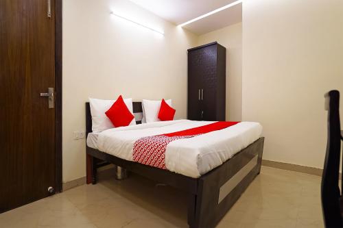 a bedroom with a large bed with red pillows at Hotel Olive Saffron in New Delhi
