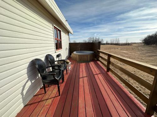 a deck with chairs and a hot tub on the side of a house at Cave Cabins in Hella