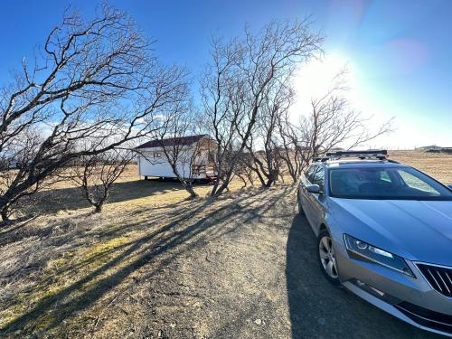 a blue car parked on a dirt road next to trees at Cave Cabins in Hella