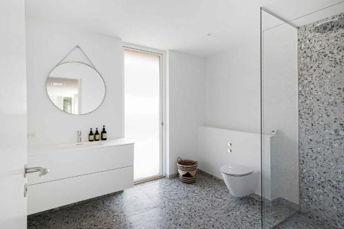 een witte badkamer met een wastafel en een spiegel bij Heavenport in Vester Sømarken