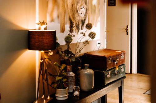 a room with a table with luggage and a lamp at Boutique Hotel Hoog Soeren in Hoog-Soeren