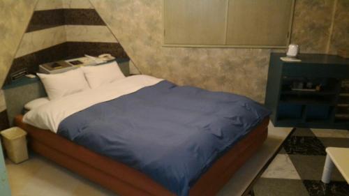 1 dormitorio con 1 cama con manta azul en Hotel Sekitei en Asahi