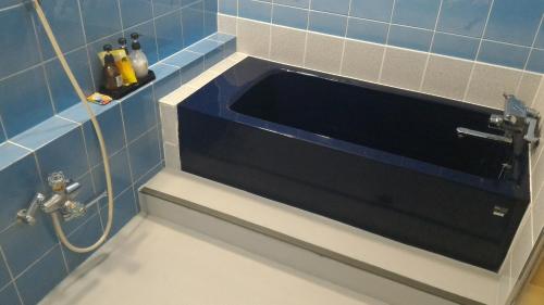 Baño de azulejos azules con lavabo. en Hotel Sekitei en Asahi