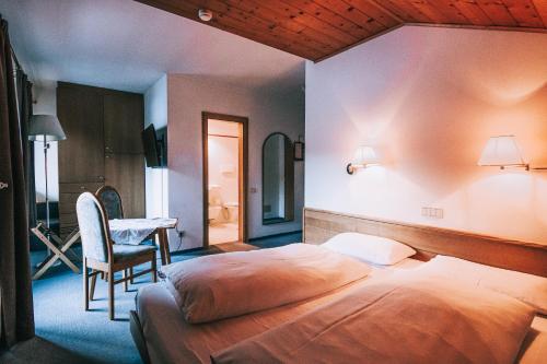 a bedroom with a bed and a table and a chair at Hotel Planac in Corvara in Badia