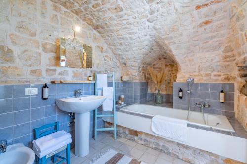 ein Badezimmer mit einem Waschbecken, einer Badewanne und einem Waschbecken in der Unterkunft Dimora Rutica in Selva di Fasano