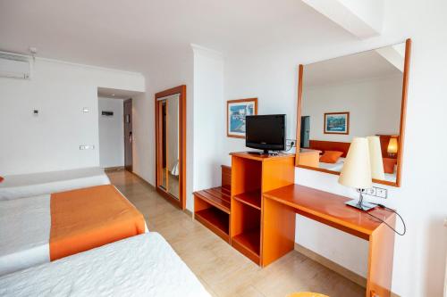 una camera da letto con un letto e una scrivania con una televisione di Hotel Risech a Roses