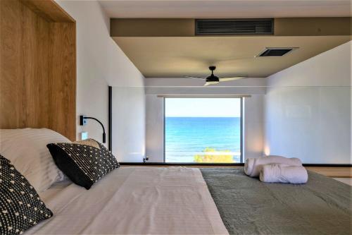 a bedroom with a bed with a view of the ocean at CUBES ON THE BEACH Athens Airport in Artemida