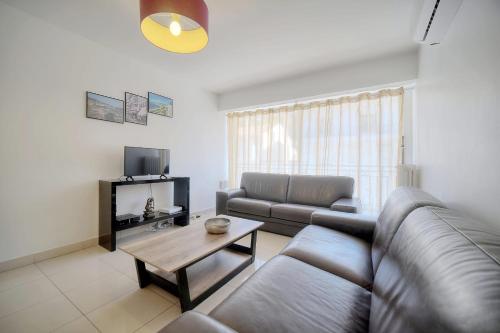 un salon avec un canapé et une table dans l'établissement IMMOGROOM - Renovated apartment - Terrace - AC, à Cannes